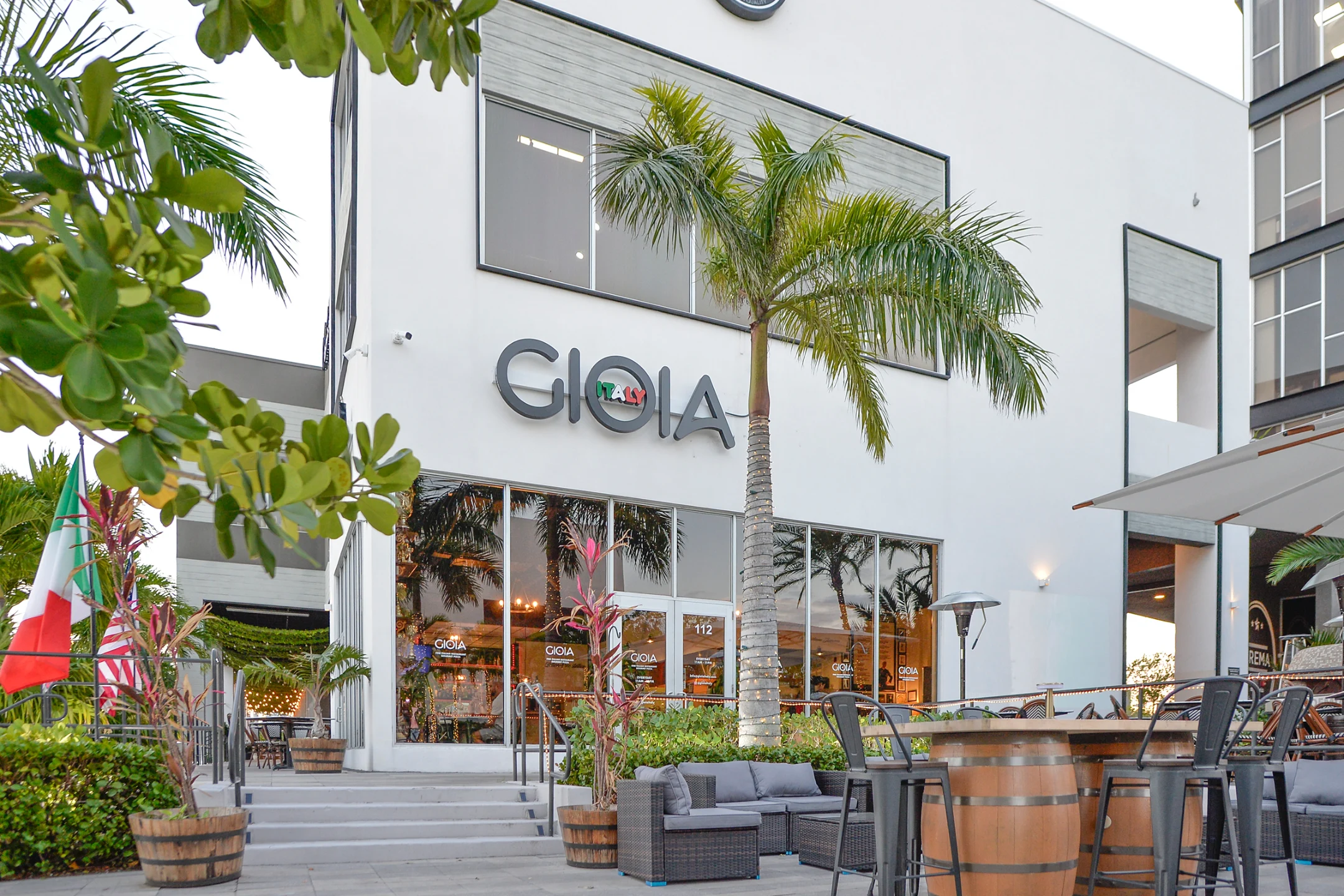 Gioia Italy restaurant exterior showcasing modern architecture and Italian elements, surrounded by greenery and outdoor seating.