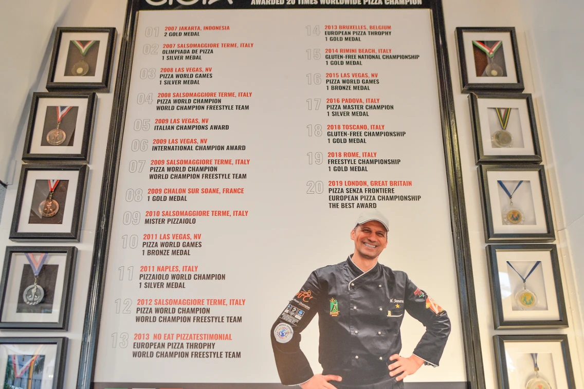 Awards and achievements display at Gioia Italy Restaurant, showcasing the accolades of a renowned pizza champion.