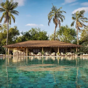 Luxurious pool area at a Nobu resort, featuring palm trees, lounge chairs, and a bar, set against a clear blue sky.