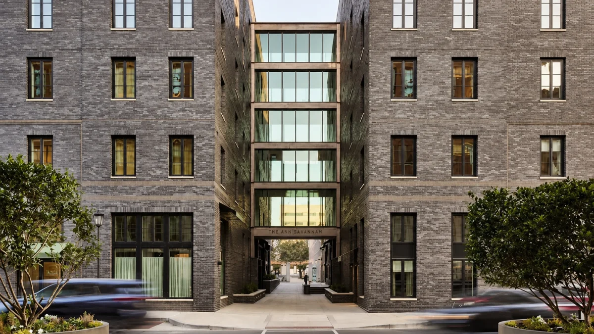 Modern architectural view of The Ann Savannah, featuring a glass entryway between two brick buildings.
