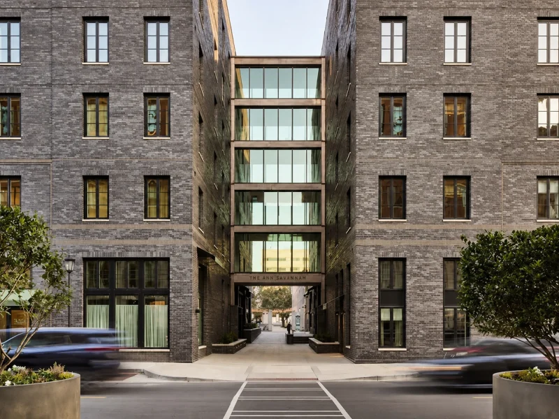 Modern architectural view of The Ann Savannah, featuring a glass entryway between two brick buildings.