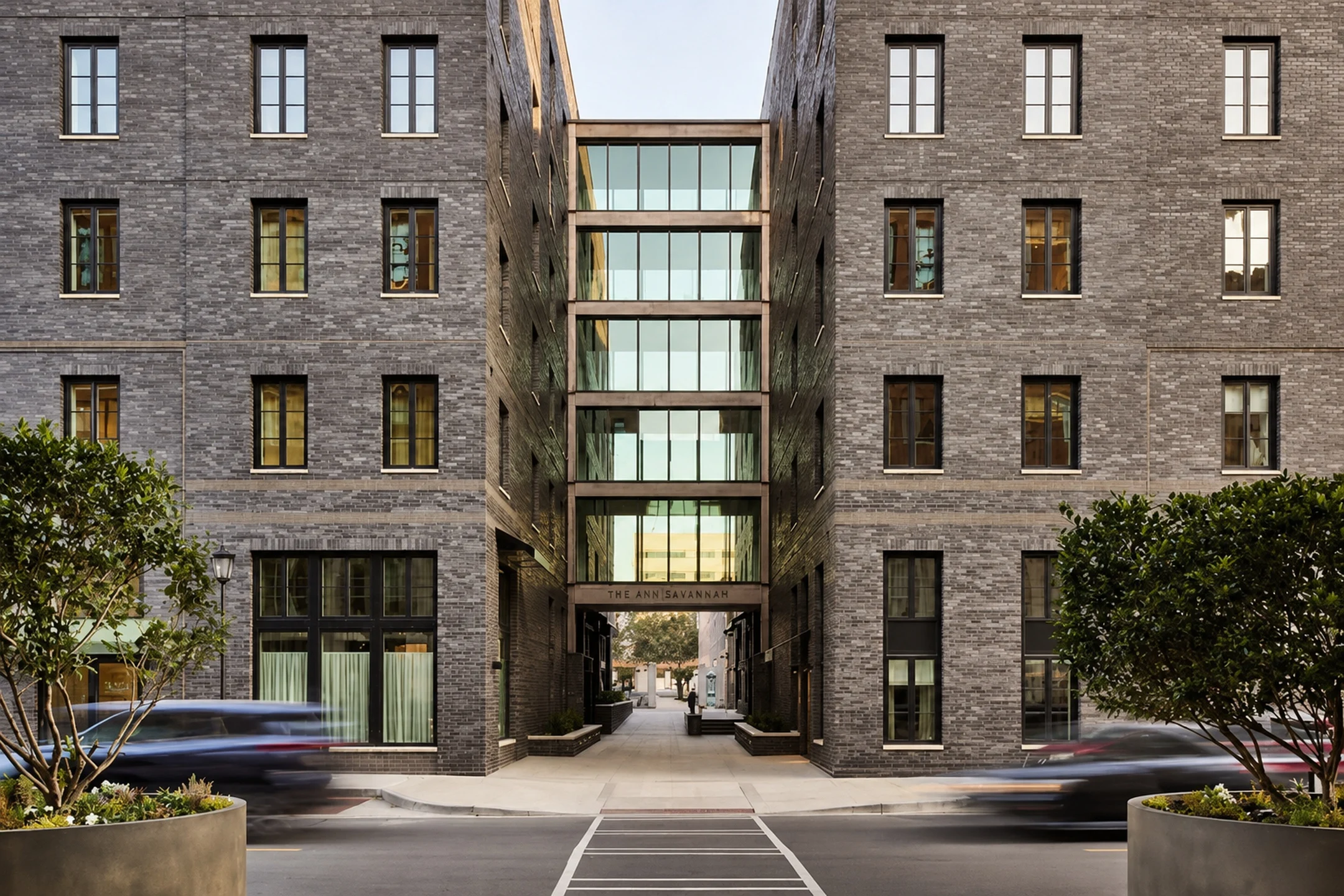 Modern architectural view of The Ann Savannah, featuring a glass entryway between two brick buildings.
