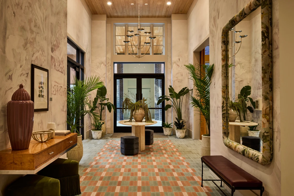 Brightly lit entryway of The Ann featuring a stylish table, plants, and a large mirror, inviting a relaxed atmosphere for guests.