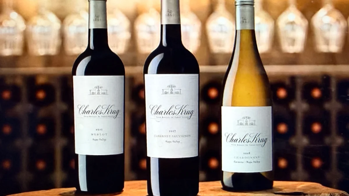 Three bottles of Charles Krug wine, including Merlot, Cabernet Sauvignon, and Chardonnay, displayed on a wooden surface.