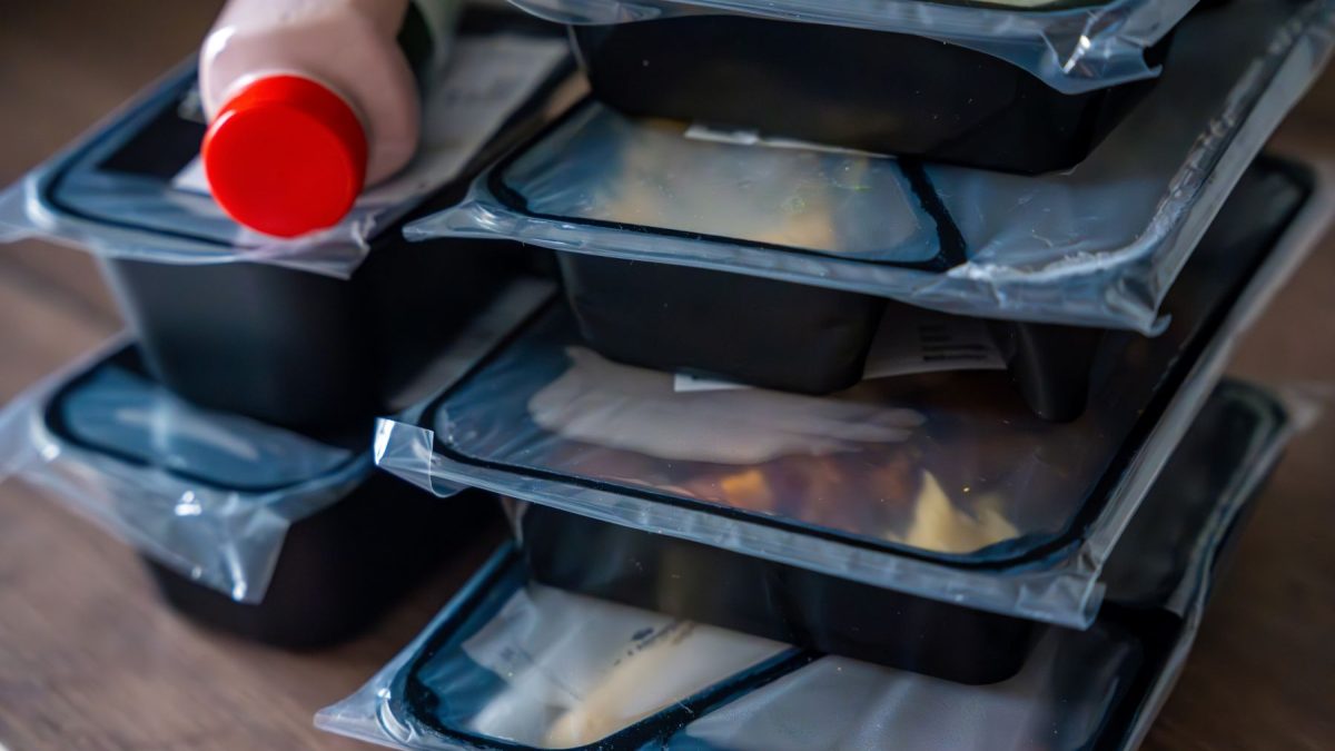 Stack of meal delivery containers with a drink bottle on top, illustrating convenient meal options for busy lifestyles.