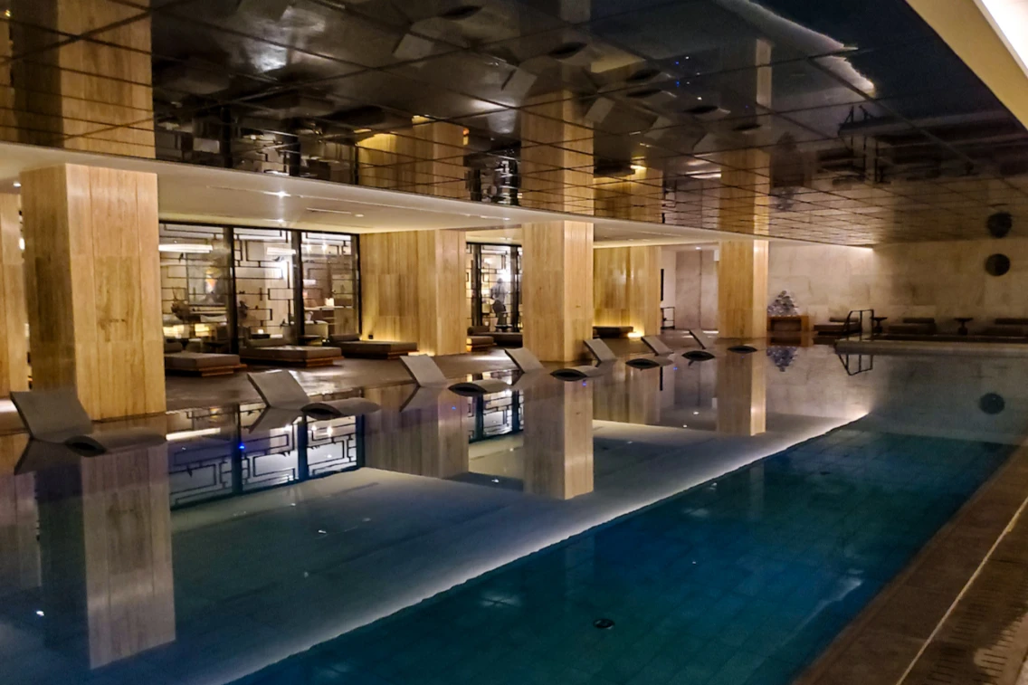 Luxury indoor pool area at the AMARA Hotel, featuring sleek design and warm lighting reflecting off the water's surface.