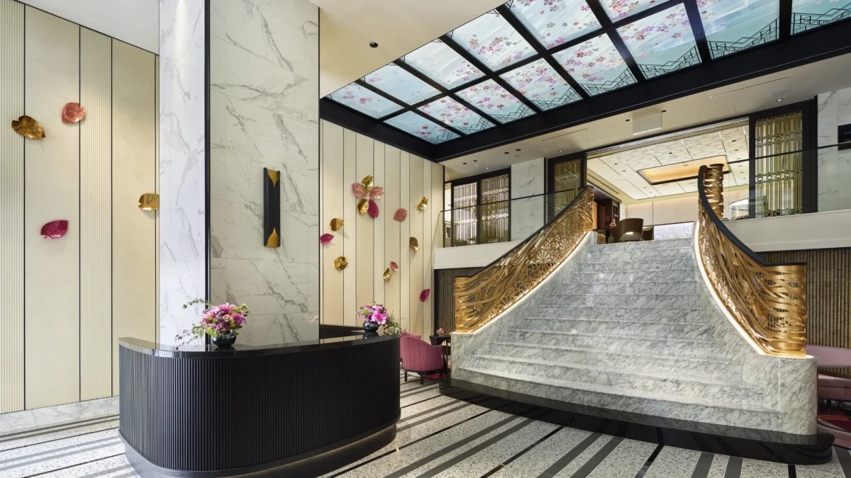 Elegant lobby of FAUCHON L’Hotel Kyoto featuring a grand staircase, marble accents, and floral decor on walls and ceiling.