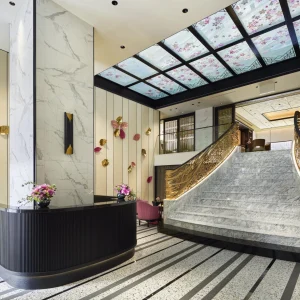 Elegant lobby of FAUCHON L’Hotel Kyoto featuring a grand staircase, marble accents, and floral decor on walls and ceiling.