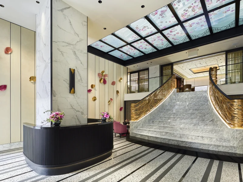 Elegant lobby of FAUCHON L’Hotel Kyoto featuring a grand staircase, marble accents, and floral decor on walls and ceiling.