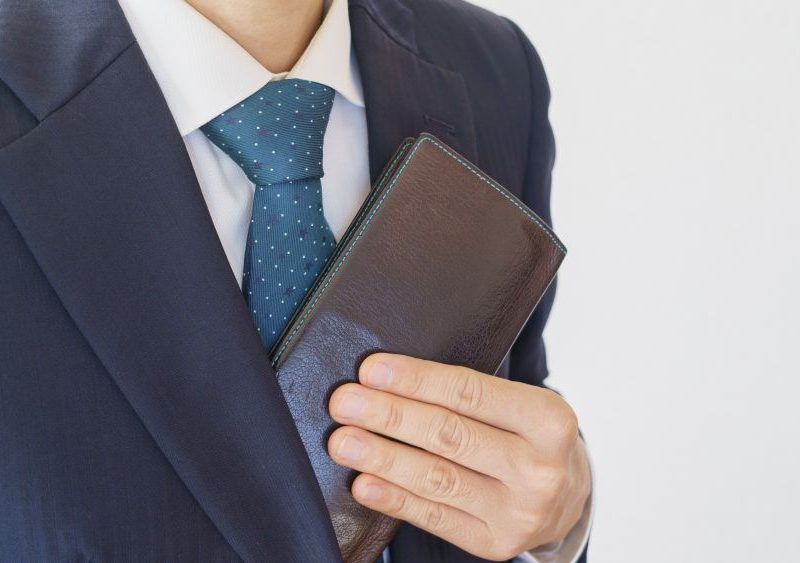 A man in a suit discreetly holds a wallet, illustrating how to carry credentials at upscale events.