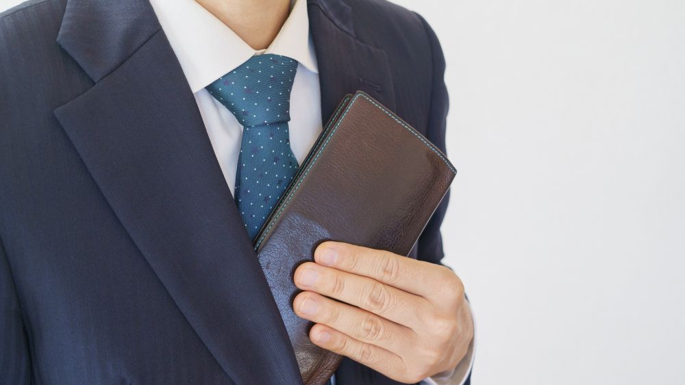 A man in a suit discreetly holds a wallet, illustrating how to carry credentials at upscale events.