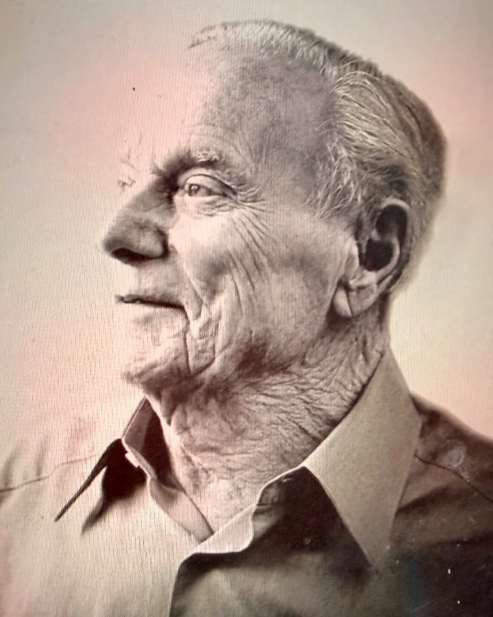 Black and white portrait of an older man with a thoughtful expression, wearing a collared shirt.
