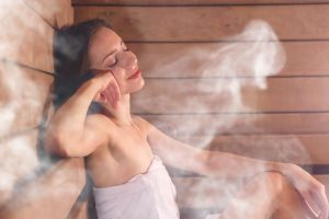 A woman relaxes in a home sauna, surrounded by steam, enjoying a moment of tranquility and warmth.