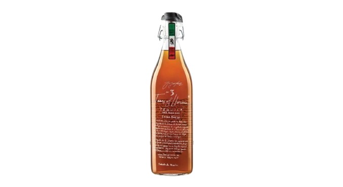 A distinctive bottle of tequila with a unique shape and amber liquid, featuring a cork stopper and decorative labeling.