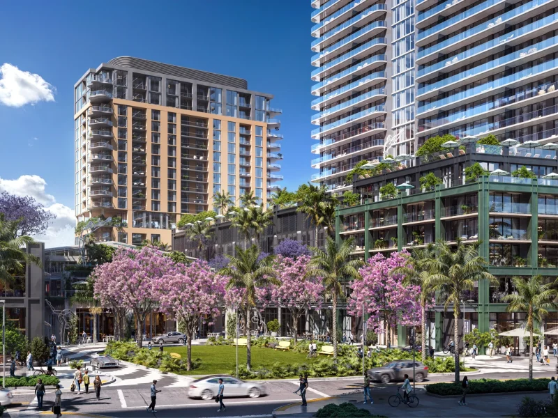 A vibrant street view of Midtown Miami featuring luxury buildings, blooming trees, and pedestrians enjoying the urban landscape.