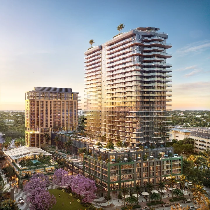 Luxury residential towers rise in Midtown Miami, surrounded by lush greenery and flowering trees.