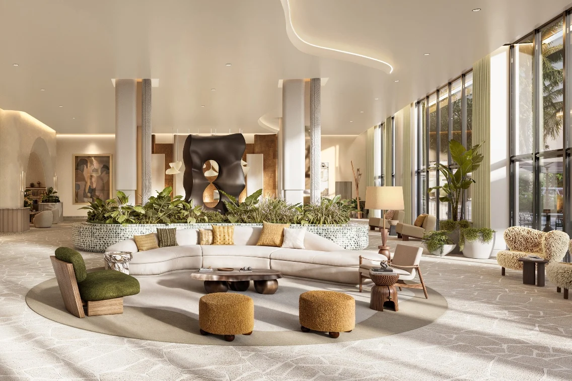 Modern lobby featuring a curved sofa, decorative ottomans, and lush greenery, showcasing luxury and comfort in Midtown Miami.