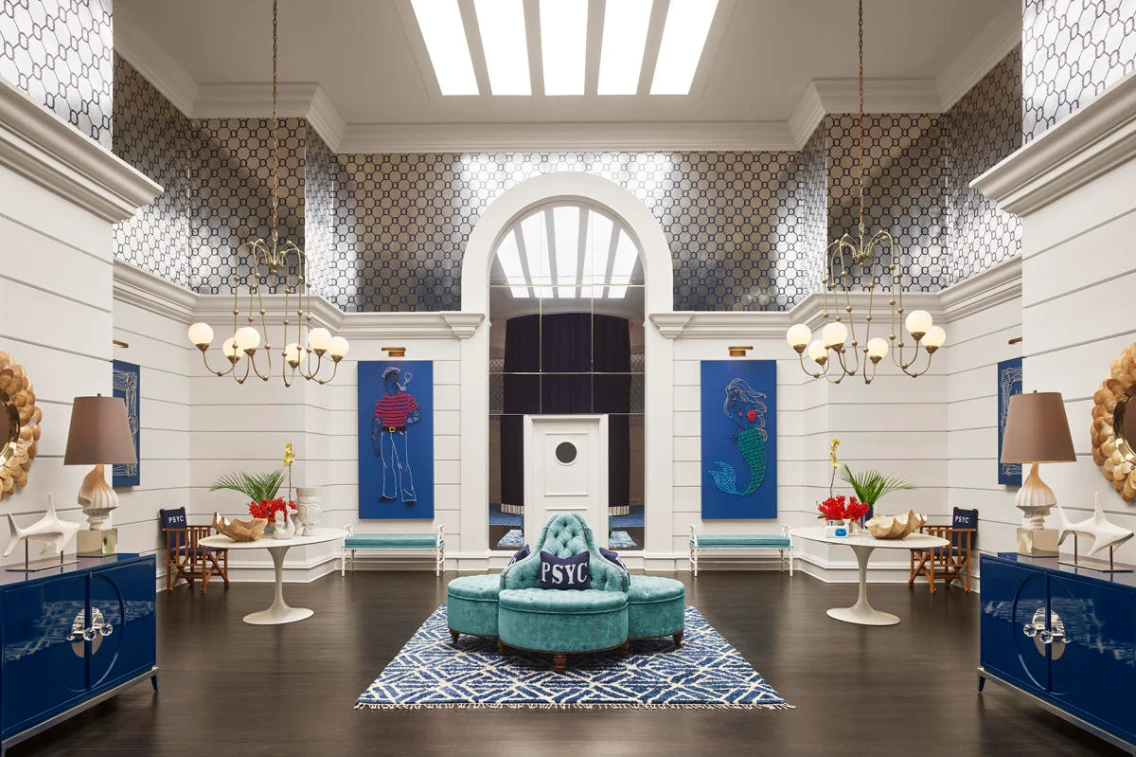Stylish lobby featuring a teal chair, blue artwork on white walls, and decorative lighting in a modern wellness space.