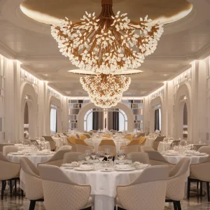Elegant dining room featuring ornate chandeliers, beautifully set tables, and stylish seating arrangements.