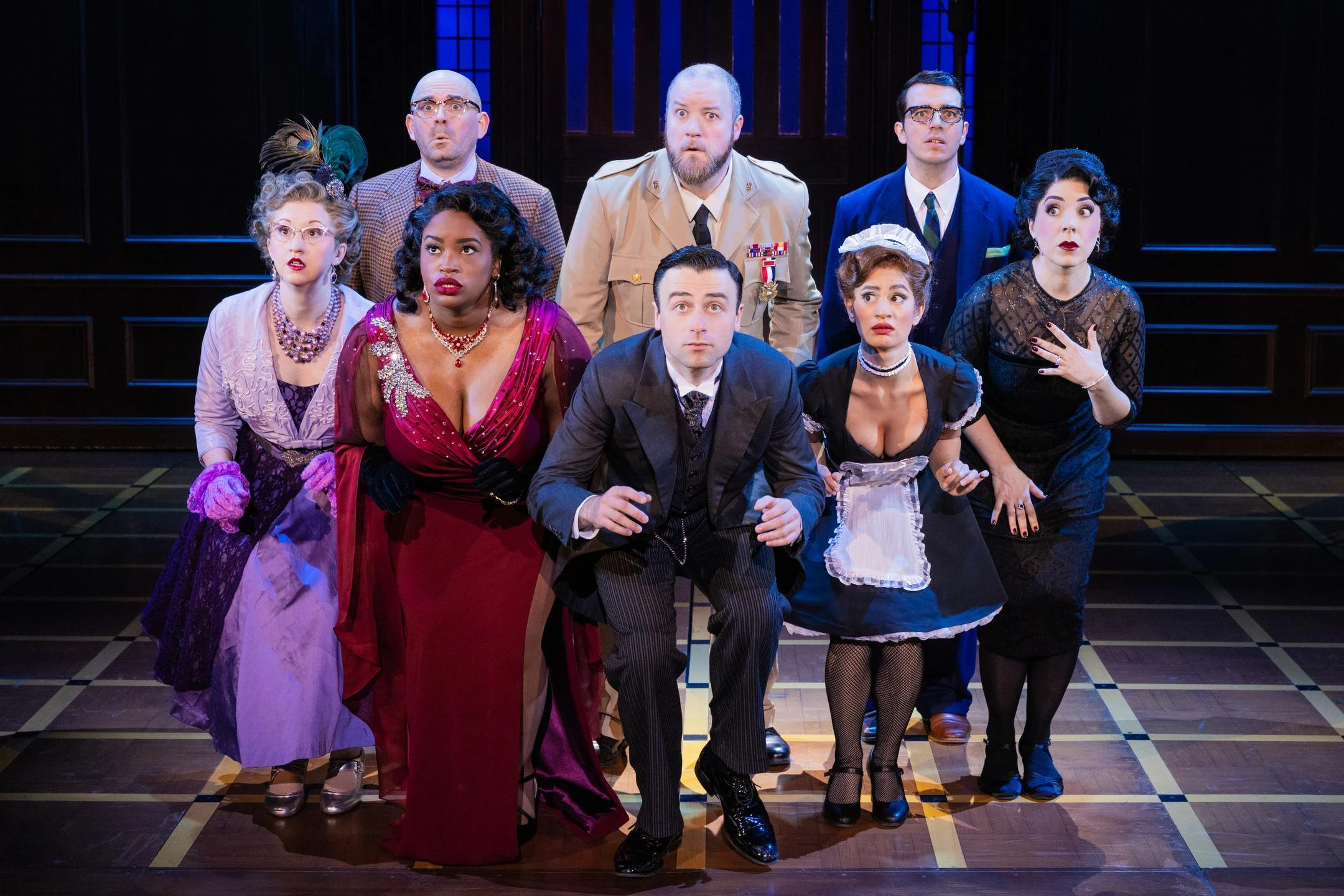Cast members perform a dramatic scene in 'Clue' on stage, showcasing a mix of surprise and intrigue.