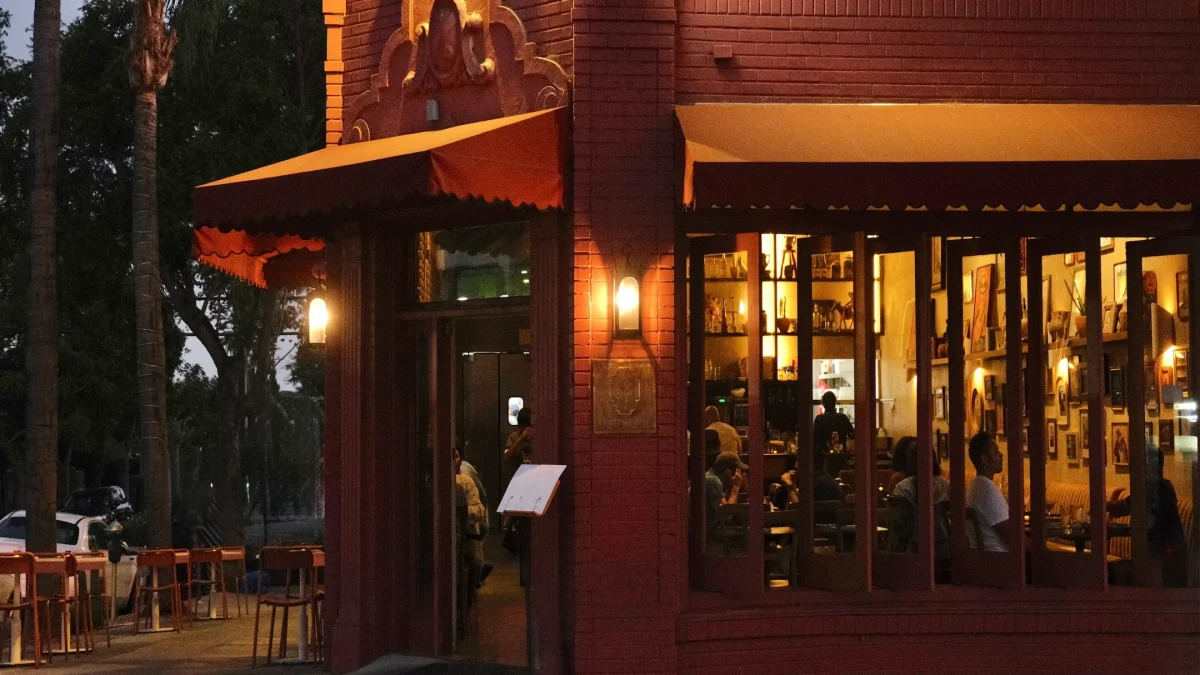 The exterior of First Of All restaurant at night, featuring warm lighting and patrons enjoying their dining experience inside.