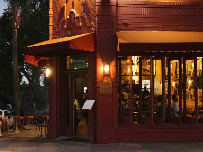 The exterior of First Of All restaurant at night, featuring warm lighting and patrons enjoying their dining experience inside.