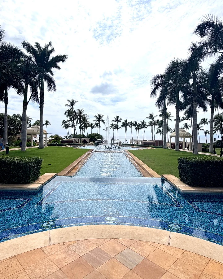 Serene view of a water feature surrounded by palm trees and well-manicured landscaping at Kilolani Spa, Grand Wailea Maui.