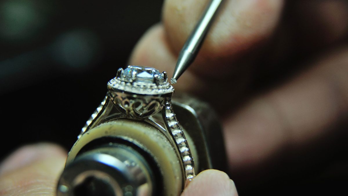 Jeweler meticulously setting a gemstone in an ornate ring, showcasing craftsmanship in bespoke jewelry.