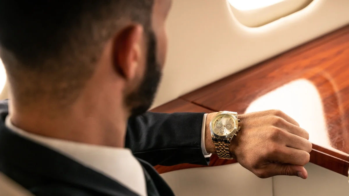 A man in a suit checks his luxury watch while seated in a private jet, highlighting the value of time in aviation.