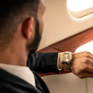 A man in a suit checks his luxury watch while seated in a private jet, highlighting the value of time in aviation.