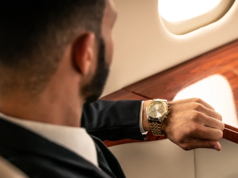 A man in a suit checks his luxury watch while seated in a private jet, highlighting the value of time in aviation.