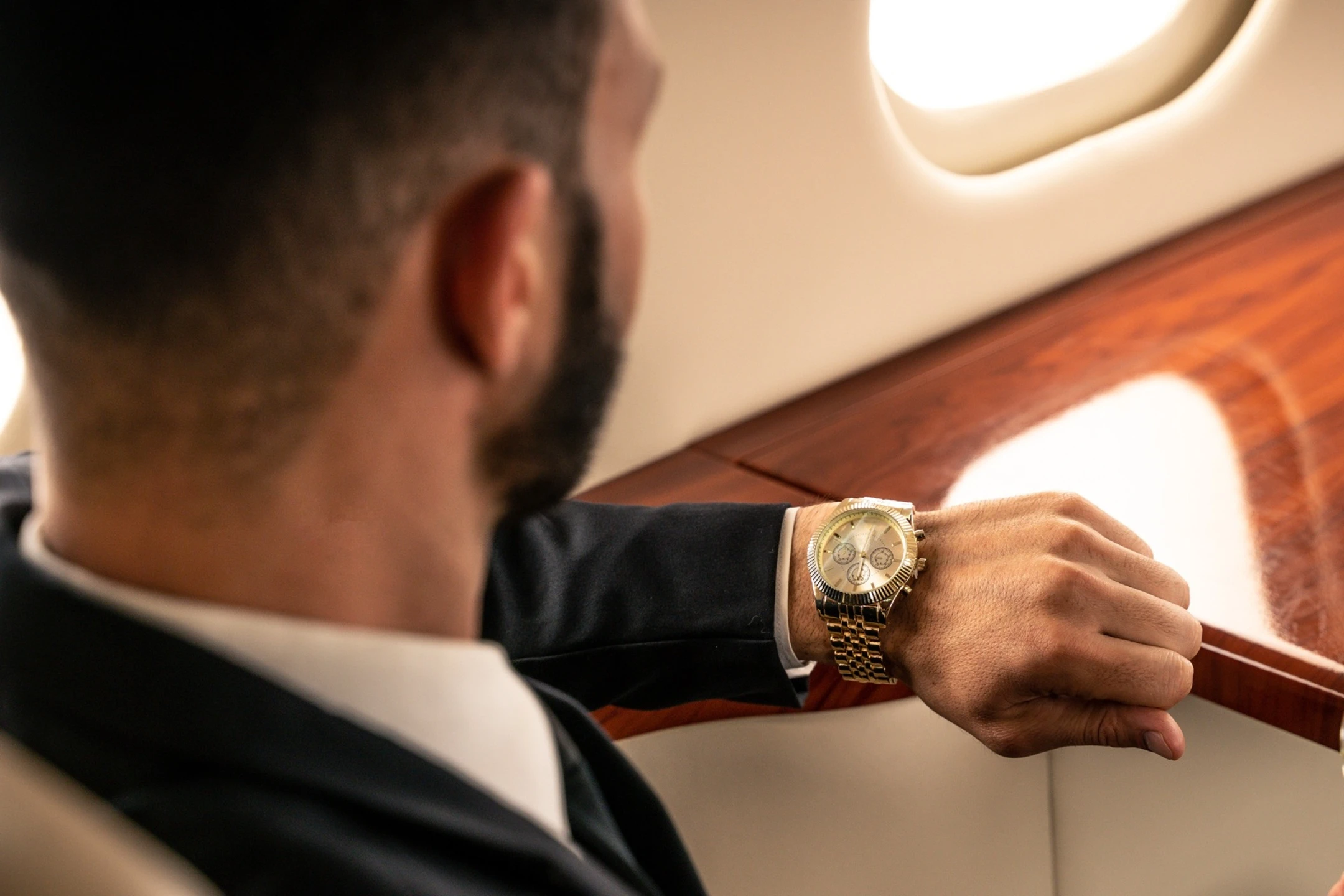A man in a suit checks his luxury watch while seated in a private jet, highlighting the value of time in aviation.