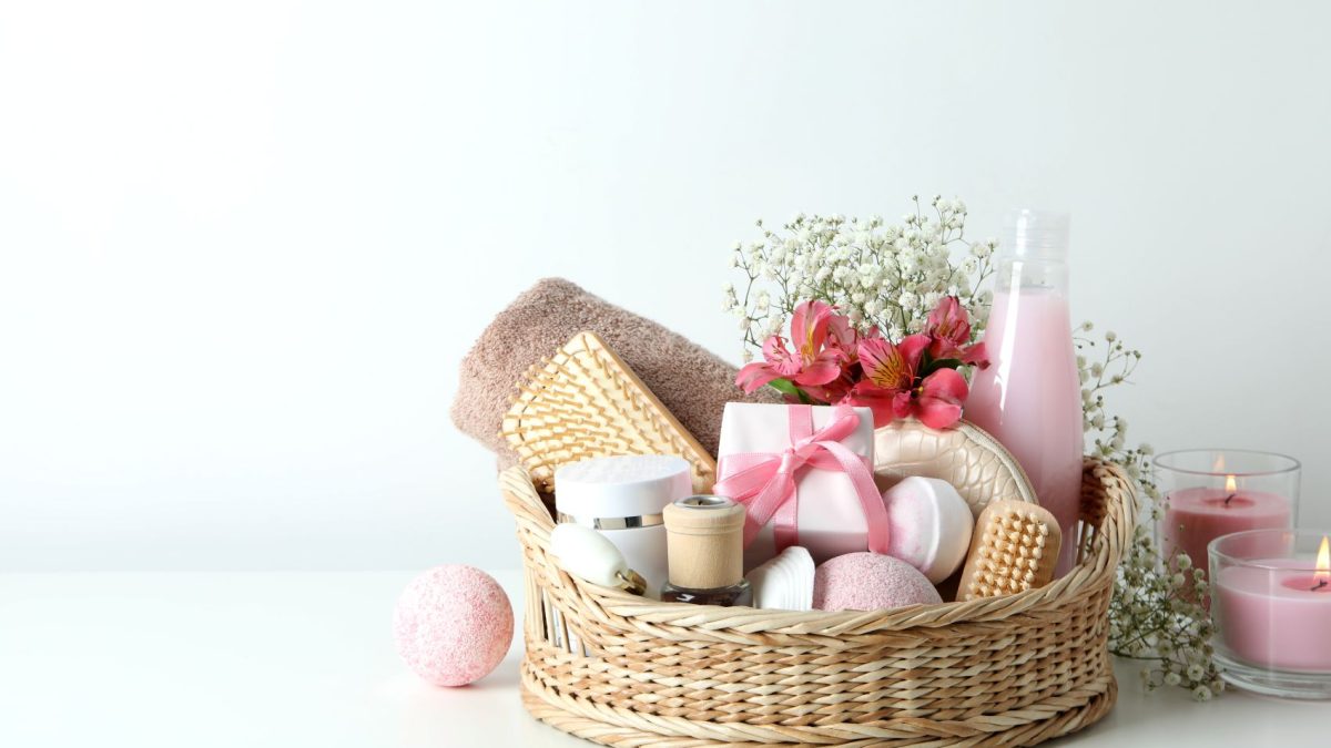 A gift basket filled with LAFCO candles, bath products, a towel, flowers, and decorative items.