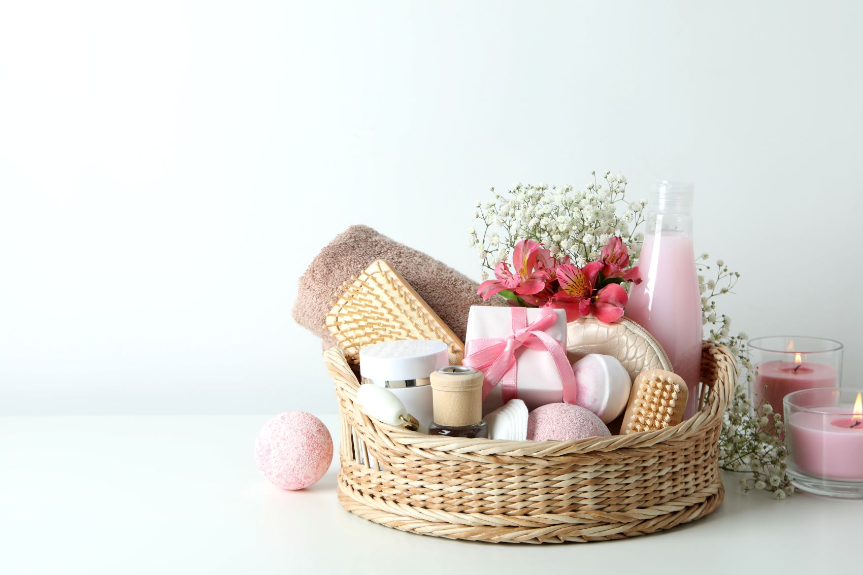 A gift basket filled with LAFCO candles, bath products, a towel, flowers, and decorative items.