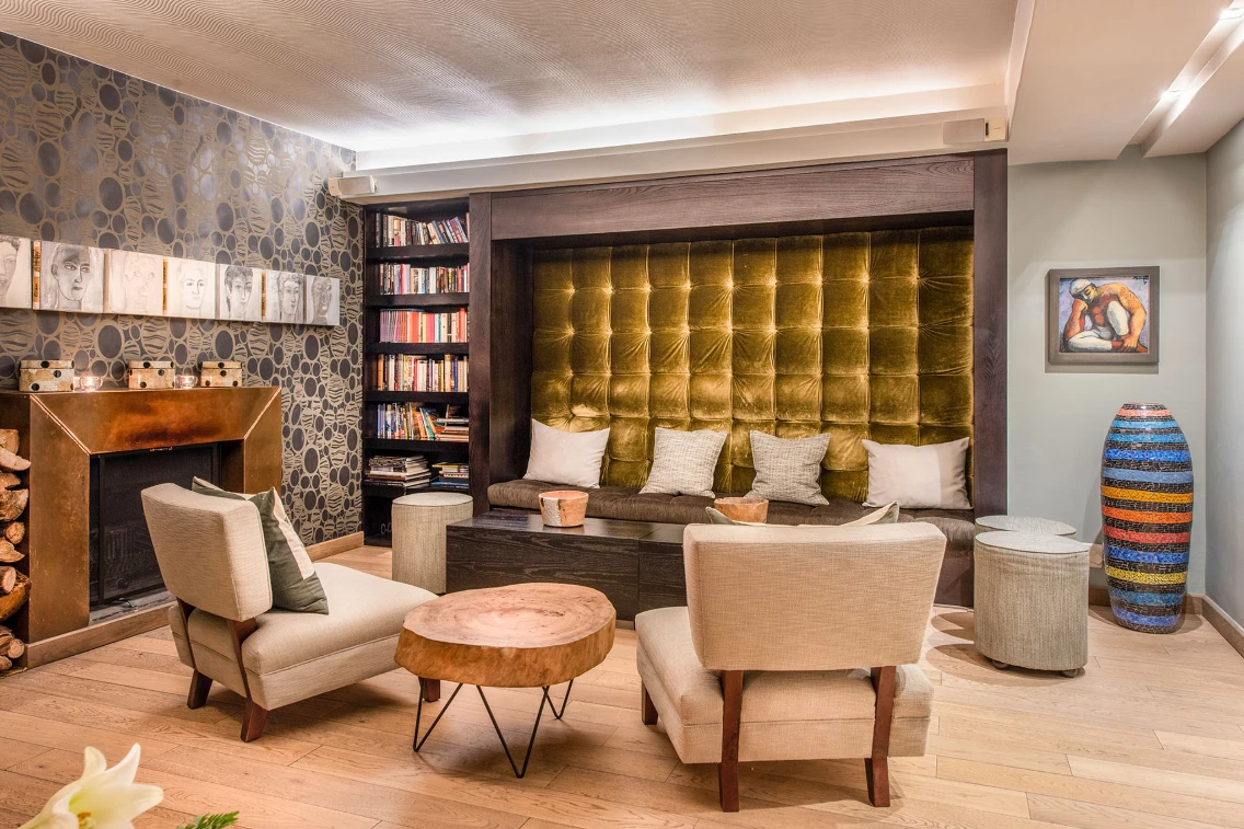 Cozy sitting area with plush seating, bookshelf, and textured wall in a stylish interior at Kensington Place.