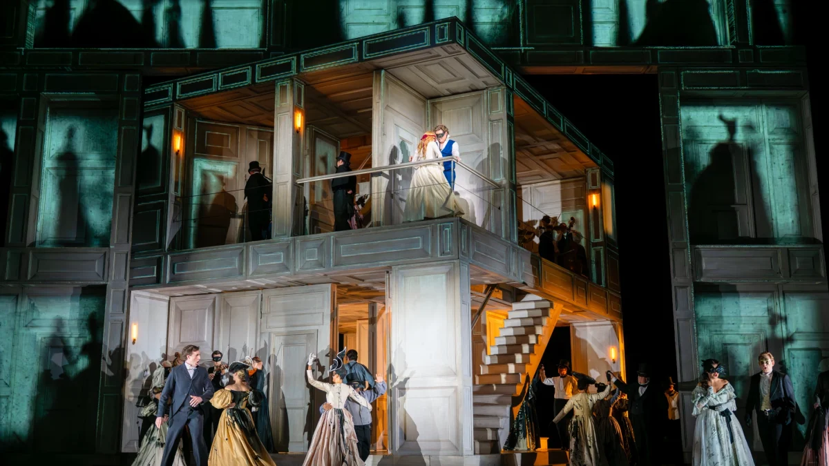 Scene from the Royal Opera’s Don Giovanni, showcasing actors in period costumes on a stylized set with dramatic lighting.