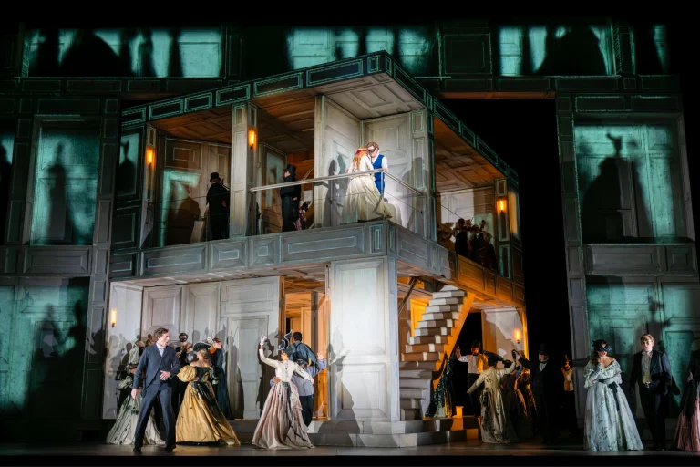 Scene from the Royal Opera’s Don Giovanni, showcasing actors in period costumes on a stylized set with dramatic lighting.