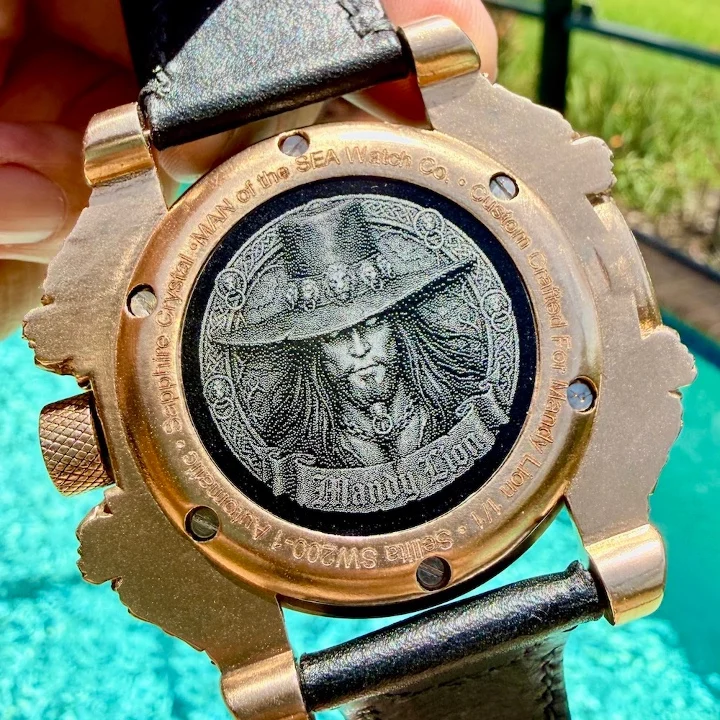 Back of a "MAN of the SEA" watch featuring an engraved design of a bearded character wearing a hat.