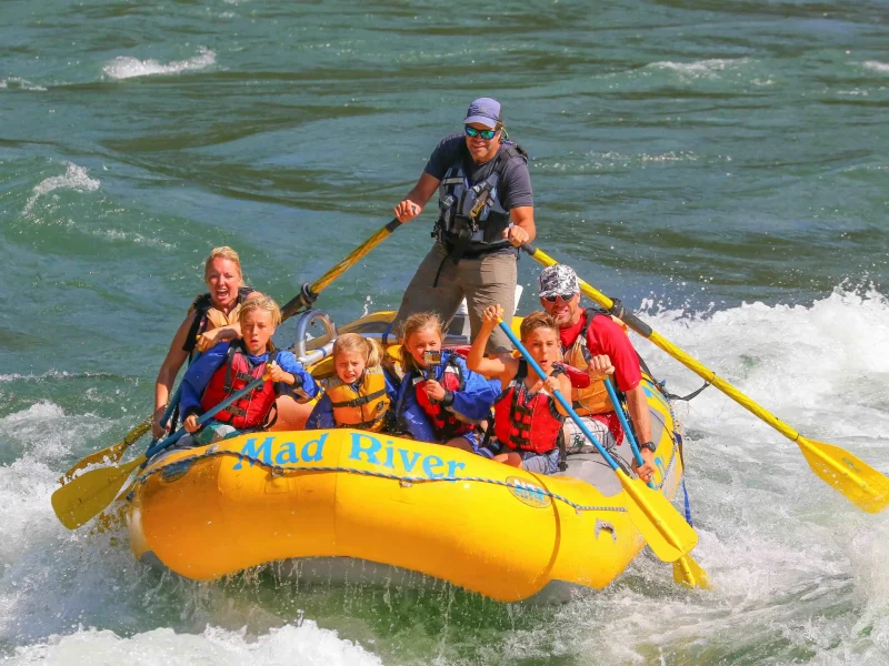 A group of people enjoying a thrilling white-water rafting experience on the Mad River.