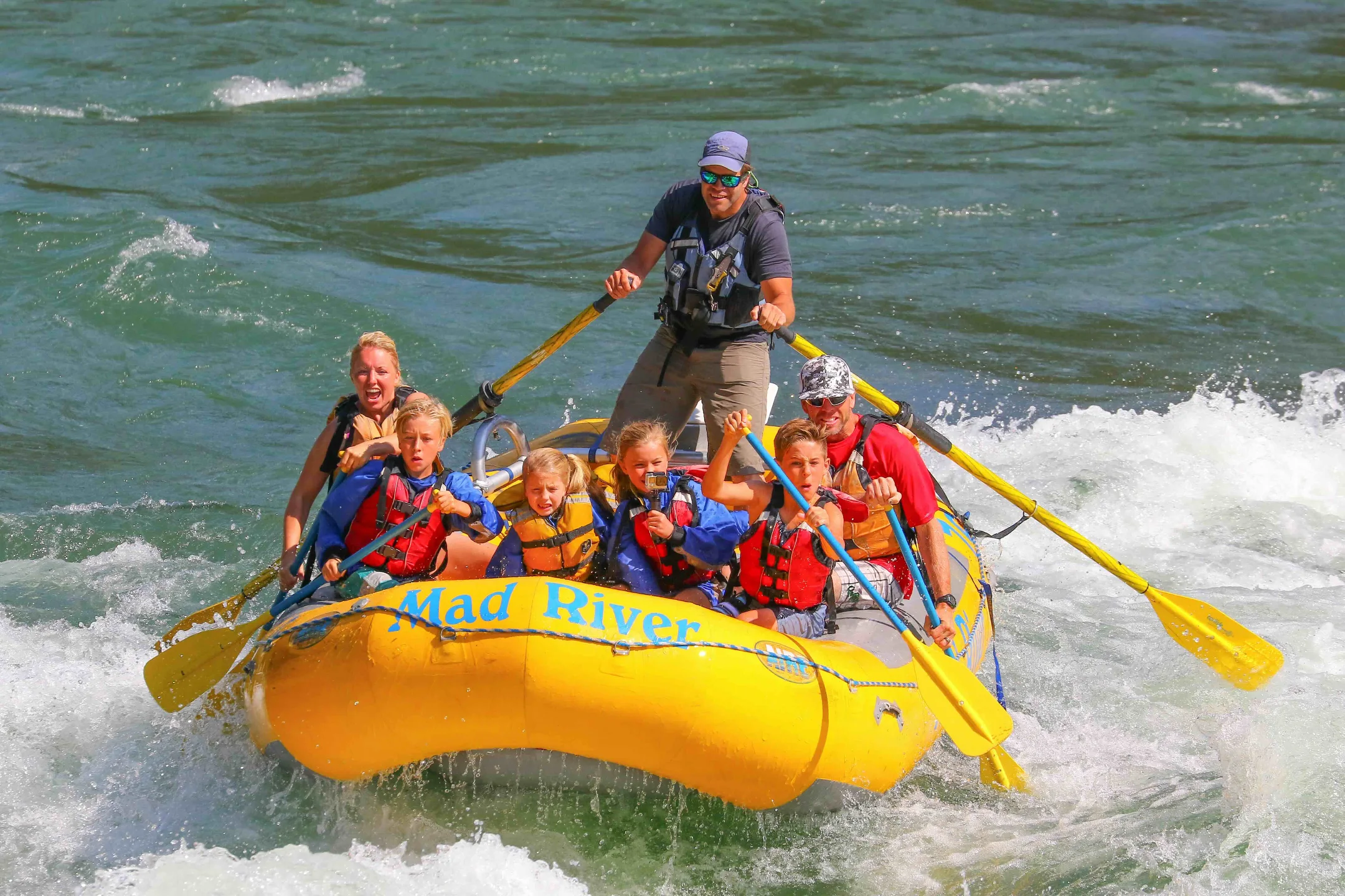 A group of people enjoying a thrilling white-water rafting experience on the Mad River.