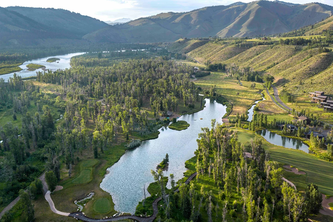 Aerial view of lush greenery and winding rivers surrounding the Sylvan Lodge in Jackson Hole, showcasing its serene landscape.