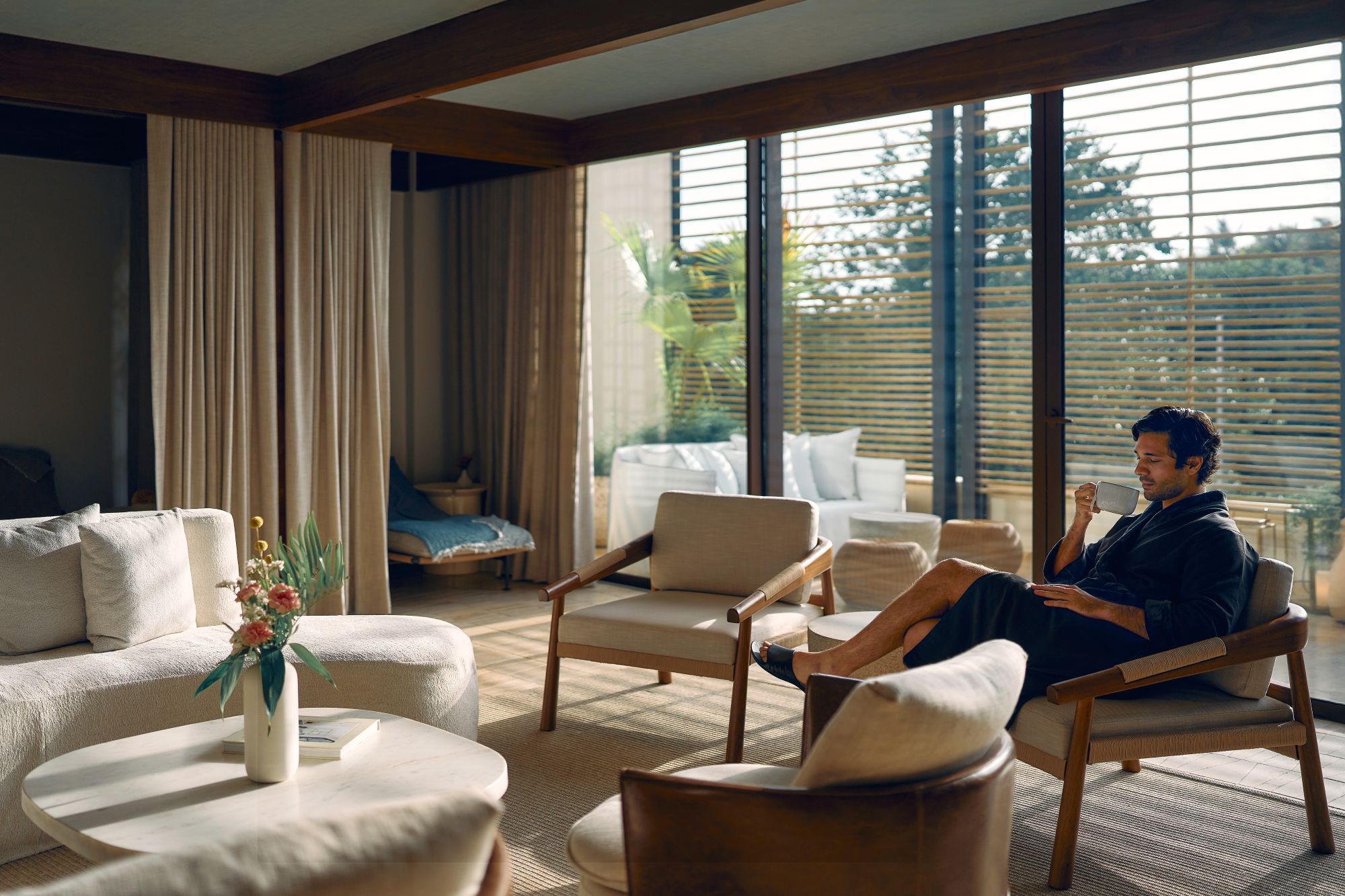A man enjoys a morning coffee in a stylish room at The St. Regis Cap Cana Resort, surrounded by elegant furnishings and natural light.