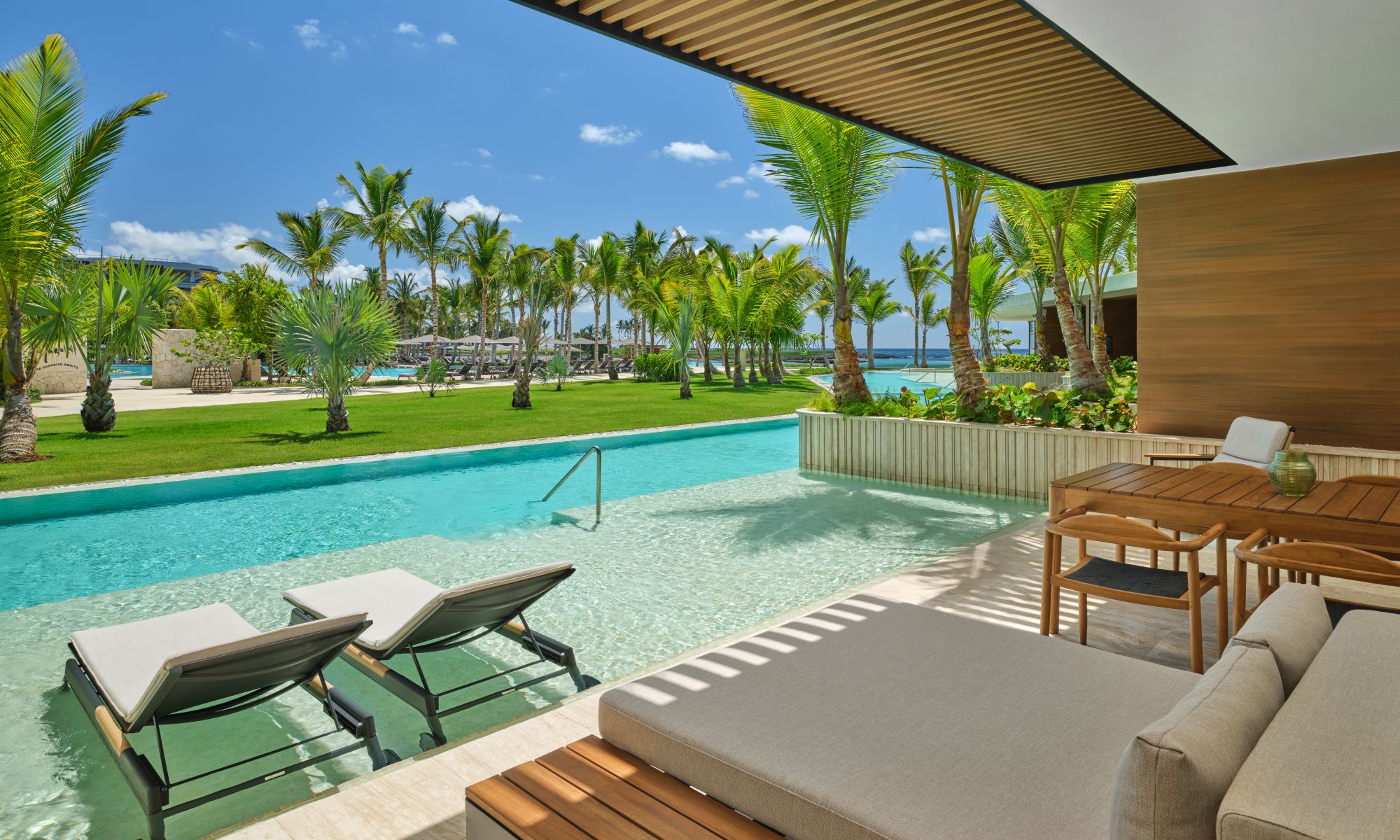 Luxurious terrace with lounge chairs overlooking a pool and palm trees at The St. Regis Cap Cana Resort.