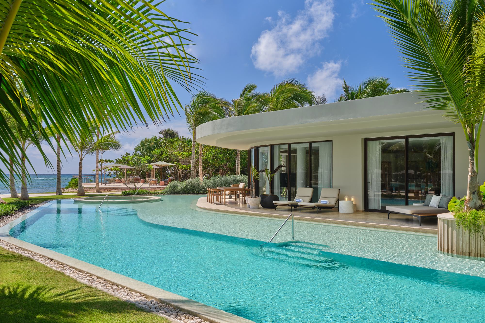 Luxurious poolside view at The St. Regis Cap Cana Resort, surrounded by lush palm trees and a serene ocean backdrop.