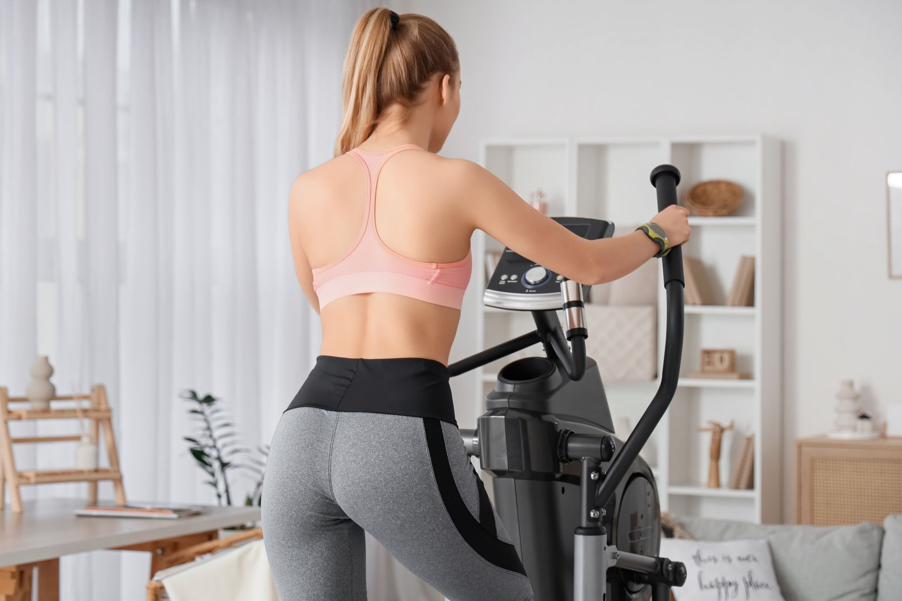 A person exercising on an elliptical machine in a bright, modern living space, focusing on cardiovascular fitness.