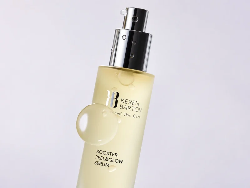 Keren Bartov Booster Peel & Glow Serum in a sleek bottle, promoting radiance and skin renewal with a glossy drop visible.