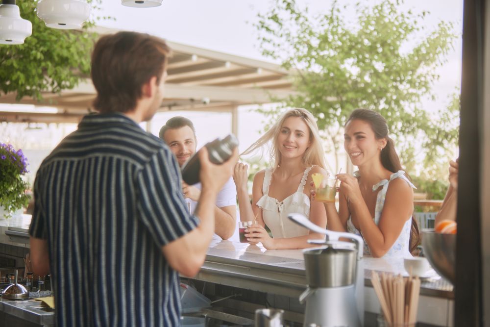 A mixologist demonstrates cocktail preparation to an engaged group of friends at a stylish home bar.