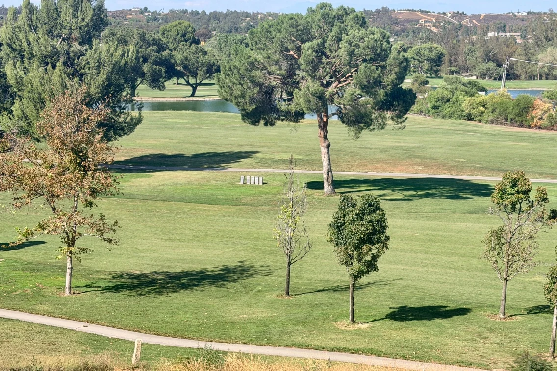 Lush green garden at Temecula Creek Inn with trees and a pond, showcasing a peaceful outdoor setting for live-fire dinners.
