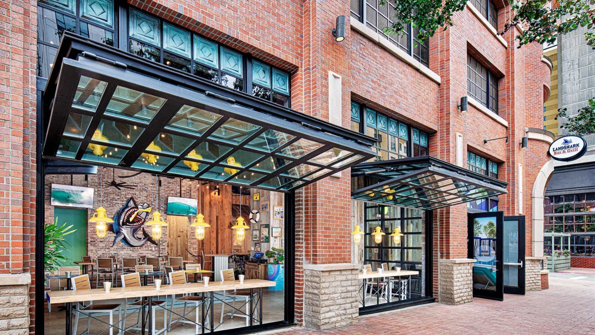LandShark Bar & Grill features a vibrant brick exterior with large windows and outdoor seating areas designed for a welcoming atmosphere.