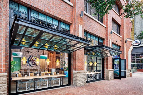 LandShark Bar & Grill features a vibrant brick exterior with large windows and outdoor seating areas designed for a welcoming atmosphere.